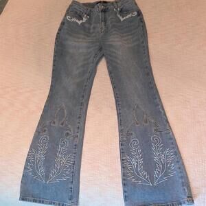 Mavericks blue jeans with white and tan embroidered designs on the lower legs